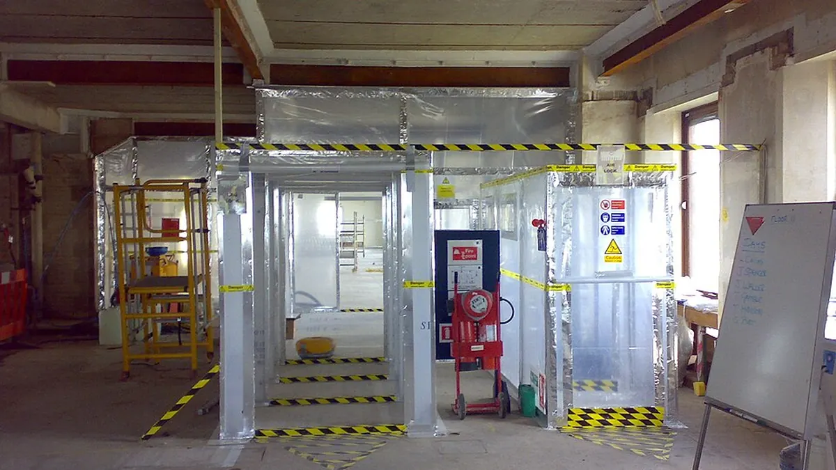 Asbestos abatement containment enclosure with warning tape and controlled work access